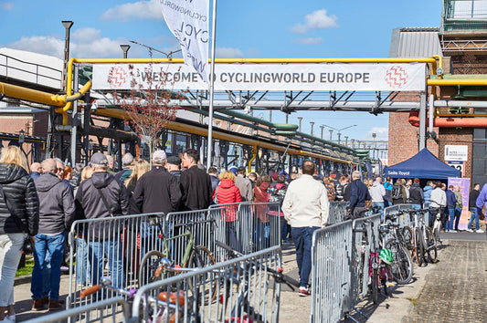 Drukke ingang van Cyclingworld Europe in Düsseldorf, bezoekers en fietsen bij de entree op een zonnige dag